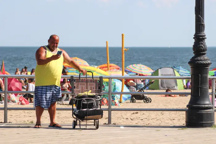 A photo of a man checking his phone at Coney Island